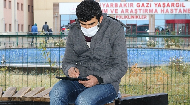 Hastane bahçesindeki banklarda uzaktan eğitimle ders veriyor