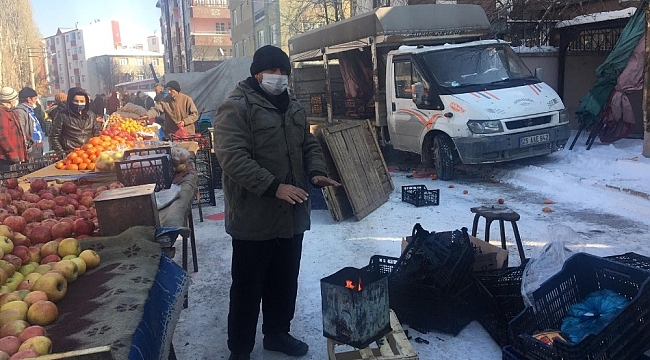 Pazarcılar soğuk havada açık alana kurdukları soba ile ısınıyor